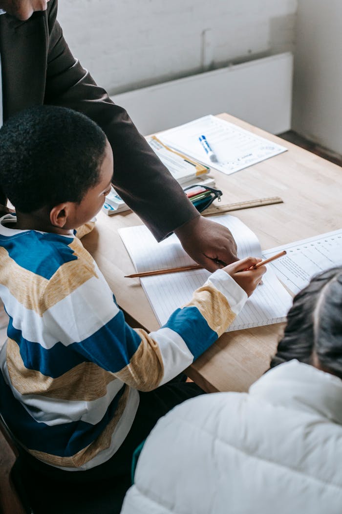 Mastering the First Impression: Your intriguing post title goes here Crop black female helping ethnic boy and girl with assignment while studying in school classroom